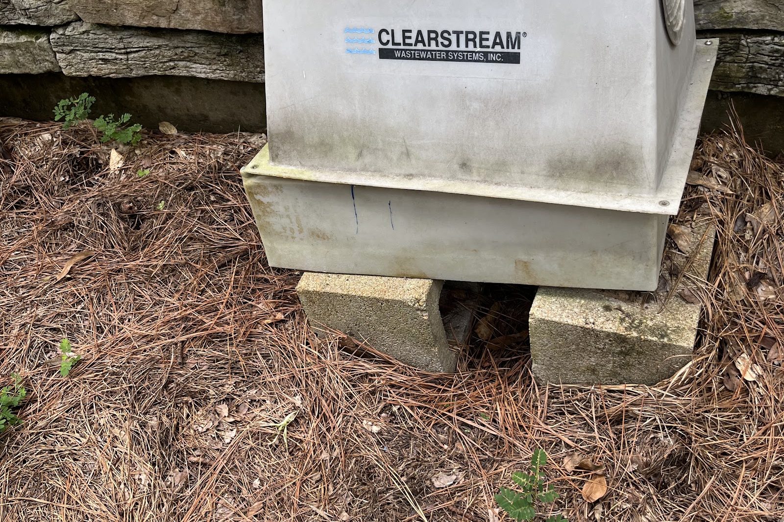 Aerobic septic system unit beside a stone retaining wall